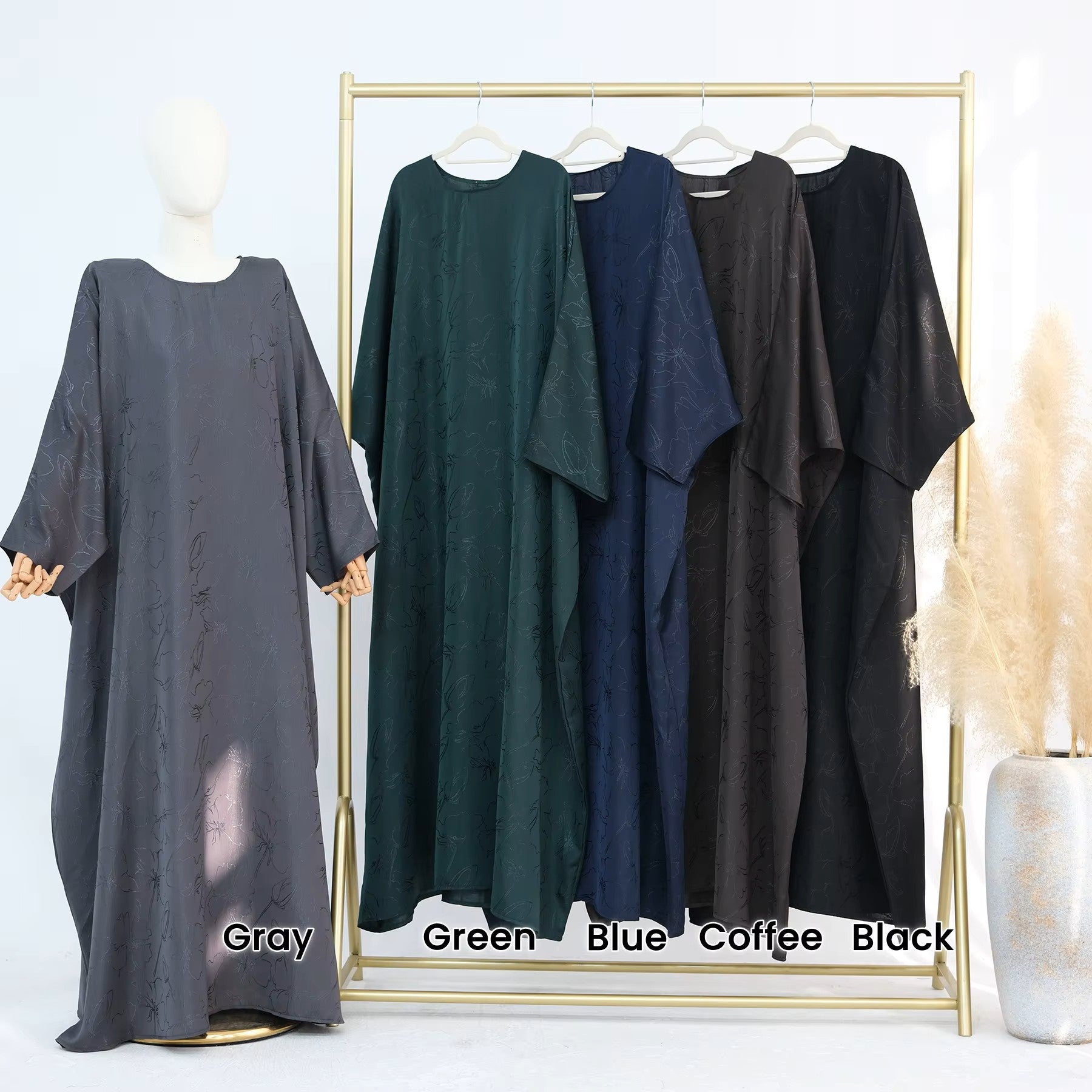Woman in a dark green abaya and gray hijab sitting in a room with white walls and decorative elements - Canada hijab dress - USA MUSLIMS