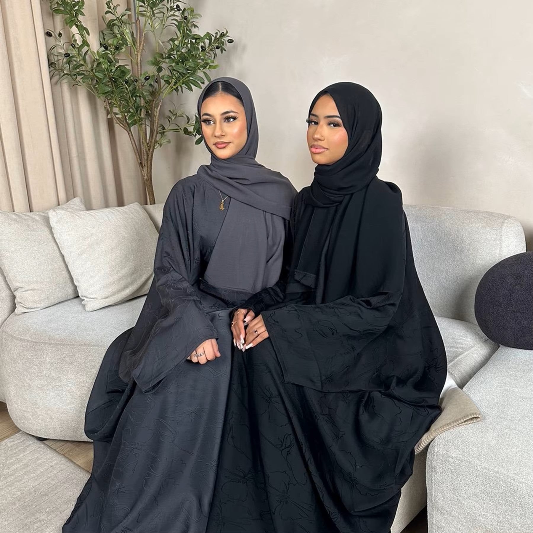 Woman in a dark green abaya and gray hijab sitting in a room with white walls and decorative elements - Canada hijab dress - USA MULSIMS