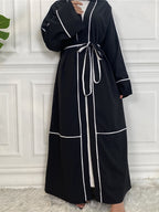 Black abaya with white trim on a white background