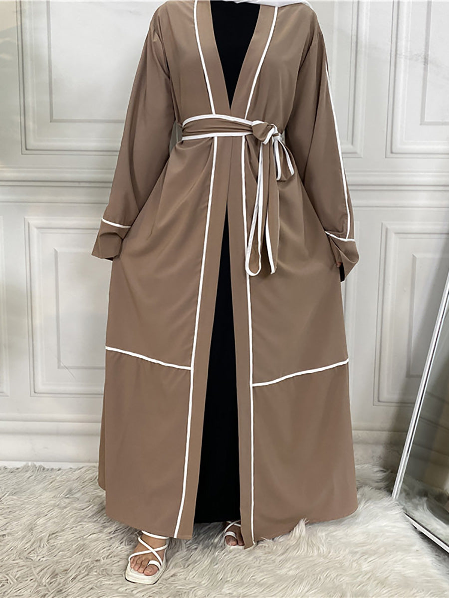 Brown robe with white trim on a person against a white paneled wall.