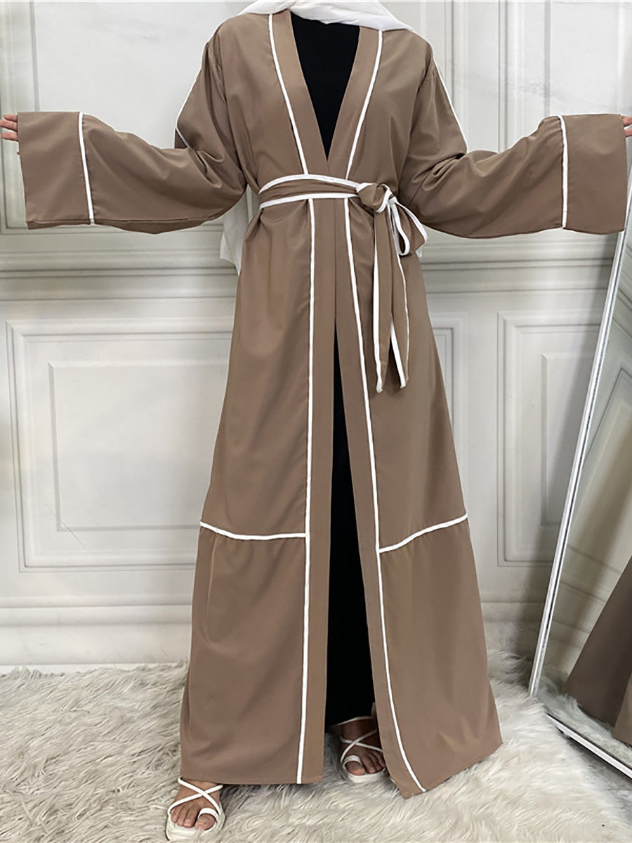 Brown robe with white trim on a person against a white paneled wall.