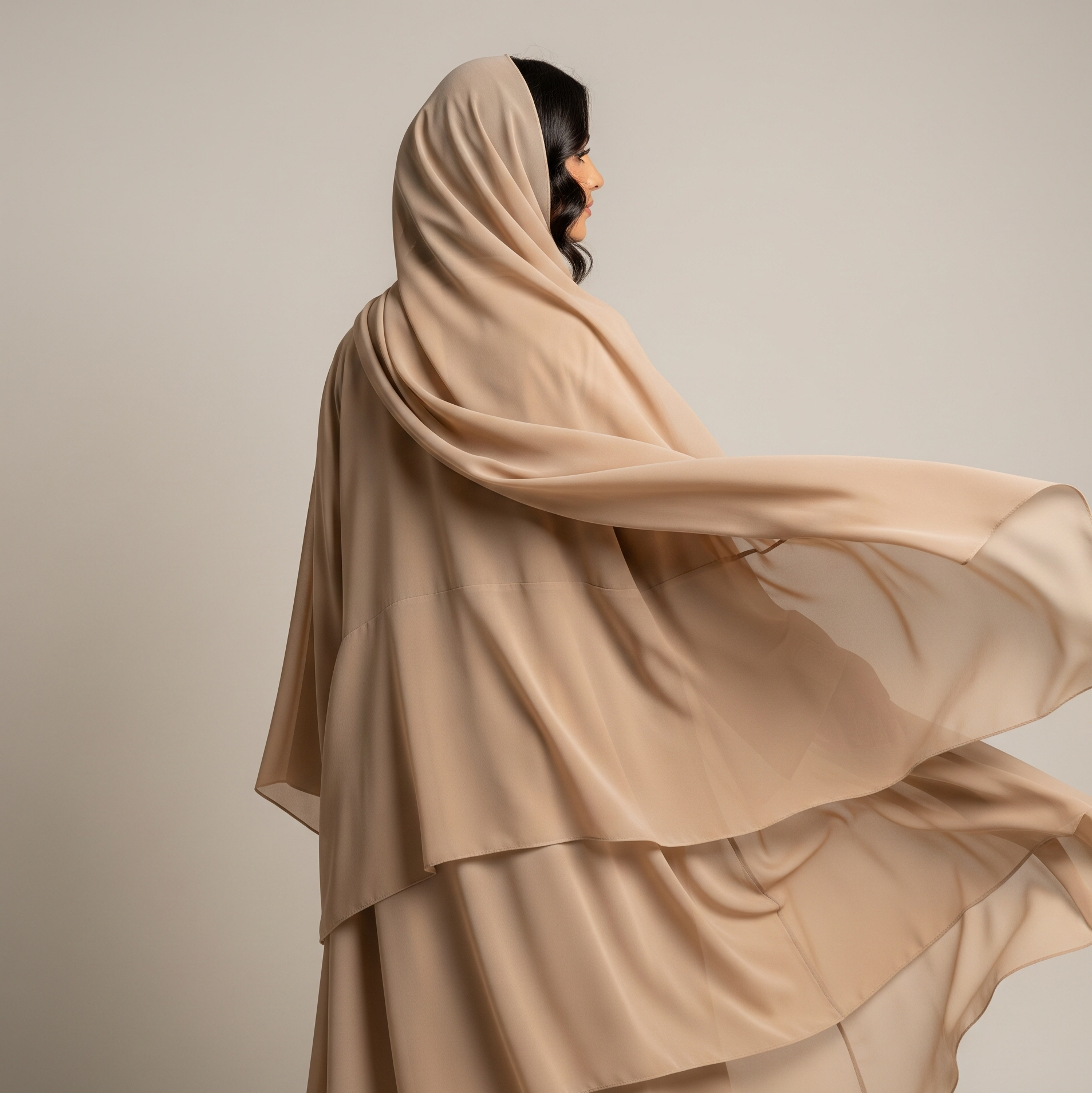 Woman wearing a beige hijab against a plain background